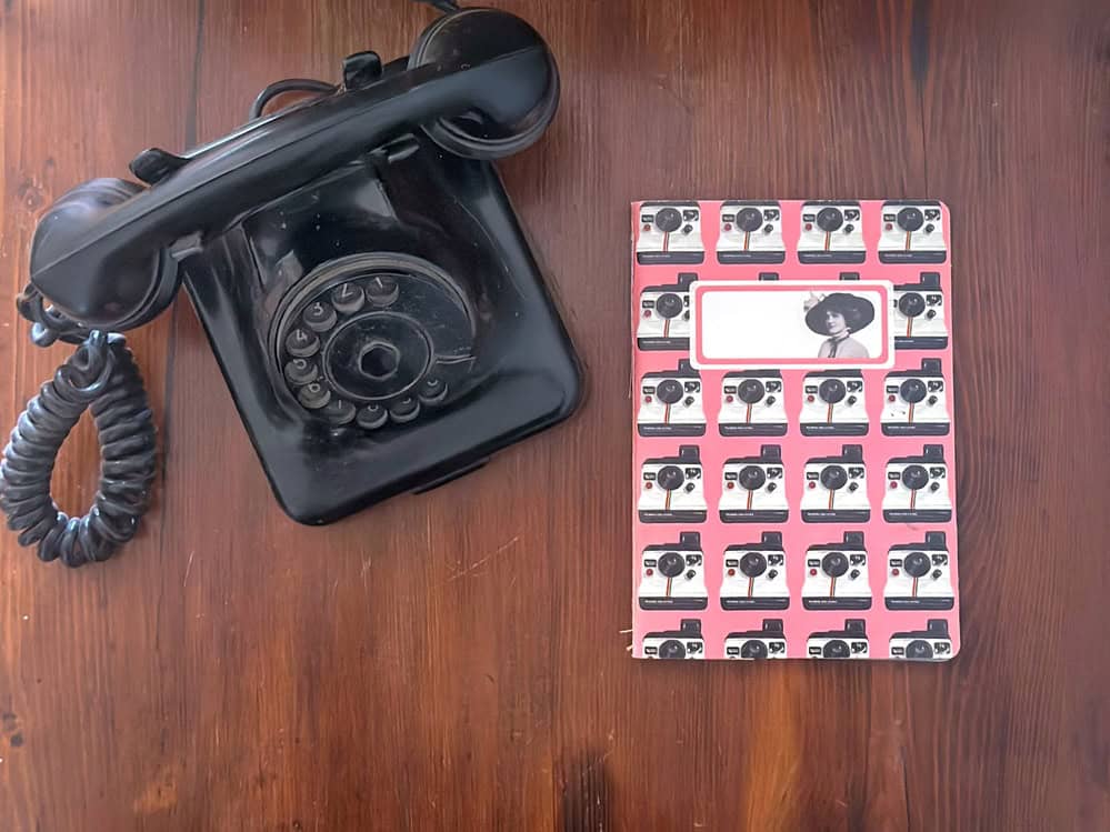 flatlay con un quaderno e un telefono, un'immagine un po' vintage che richiama l'idea della comunicazione analogica